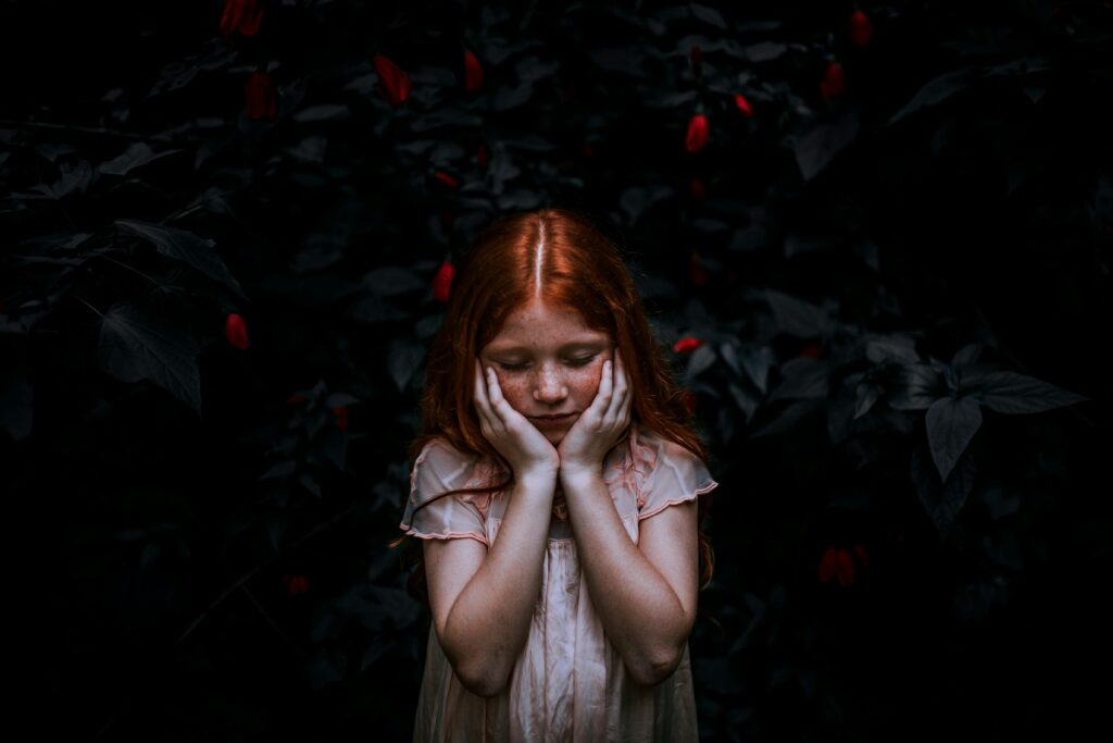 Child looking concerned in dark but peaceful setting. Cover photo for an article on Child Anxiety Therapy